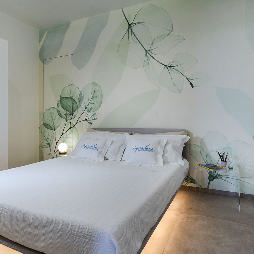 Camera da letto moderna con parete decorativa con illustrazioni di foglie e farfalle, letto con lenzuola bianche