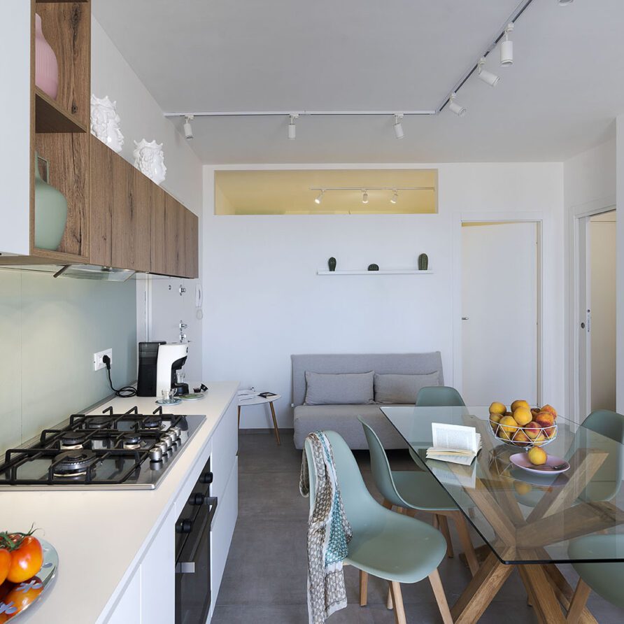 Interno di un soggiorno e cucina moderni con soggiorno arredato e zona pranzo con sedie trasparenti