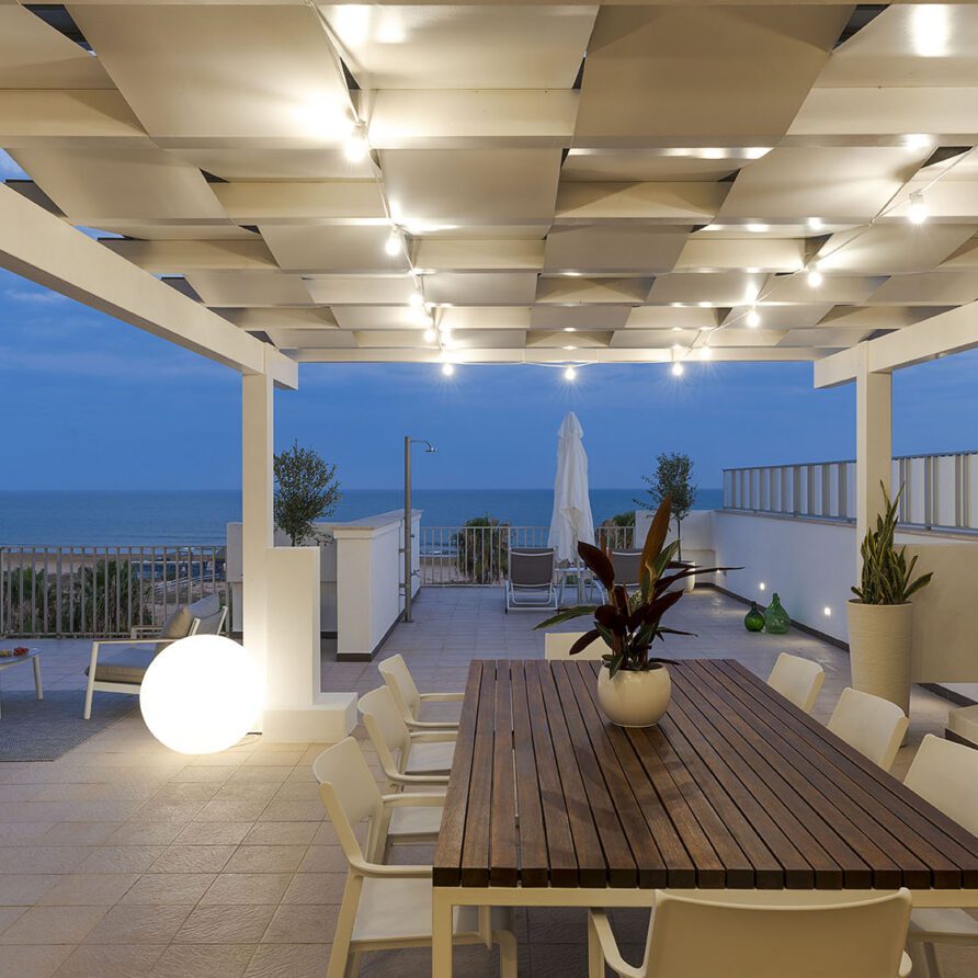 Terrazza panoramica all'aperto con arredamento elegante e vista sul mare al tramonto