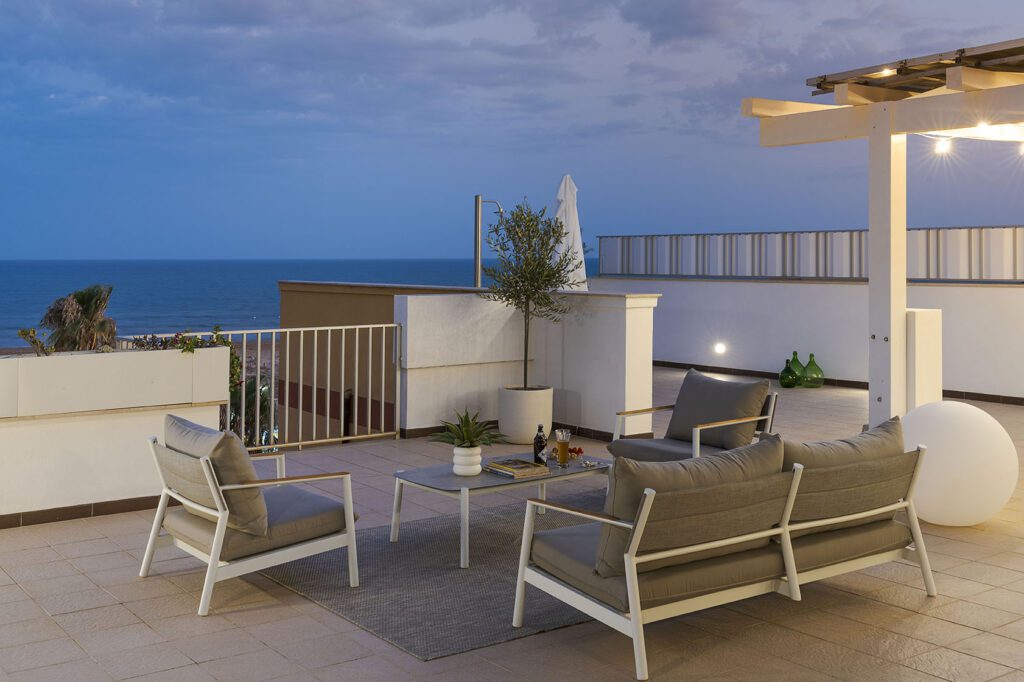 Terrazza moderna con divani e poltrone, vista panoramica sul mare e sul cielo sereno di sera