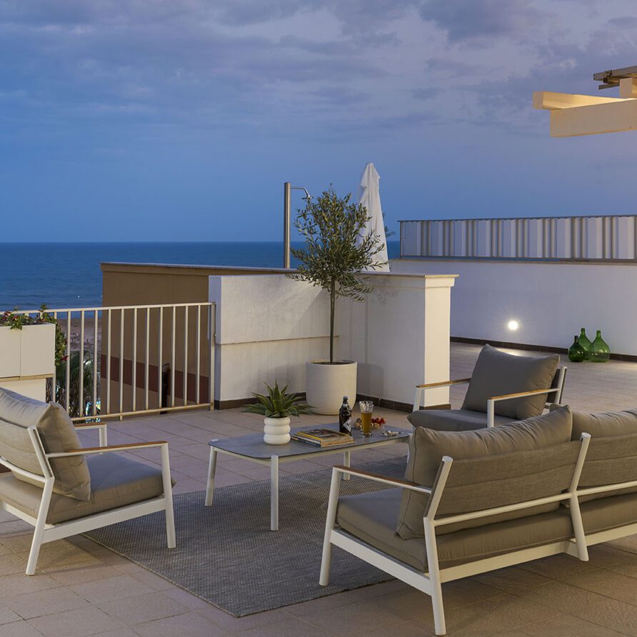 Terrazza moderna con divani e poltrone, vista panoramica sul mare e sul cielo sereno di sera