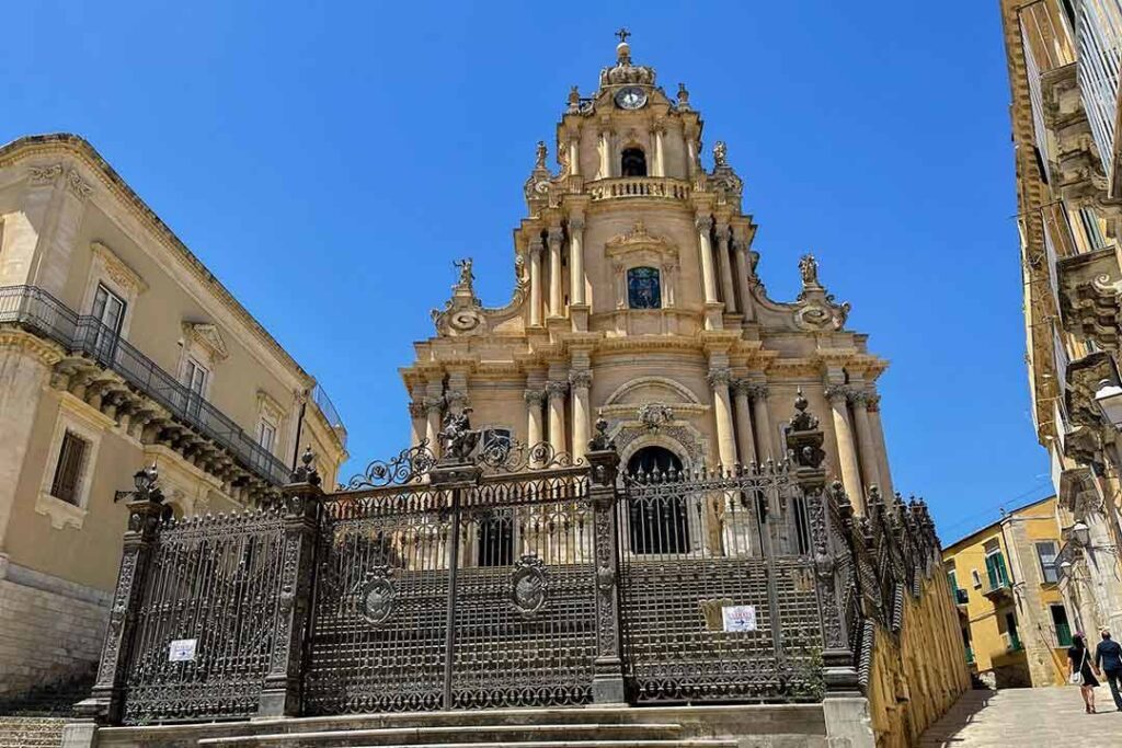 Chiesa storica barocca con facciata ornata e torre centrale sotto un cielo azzurro