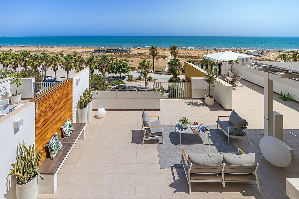 Terrazza solarium con arredi moderni e vista sulla spiaggia e il mare azzurro