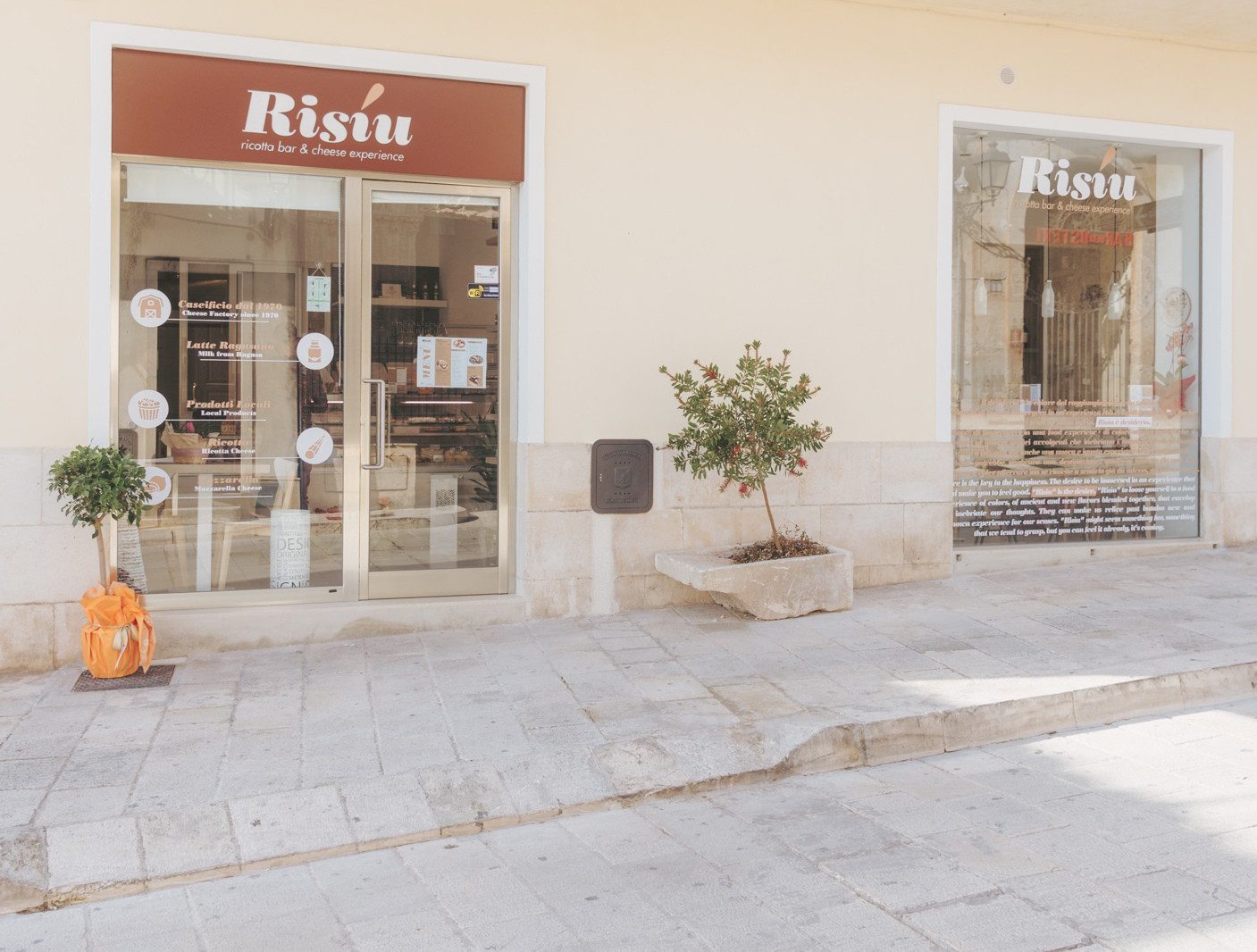 Facciata di un negozio con insegna Rissu, vetrine con decorazioni e pianta davanti su marciapiede