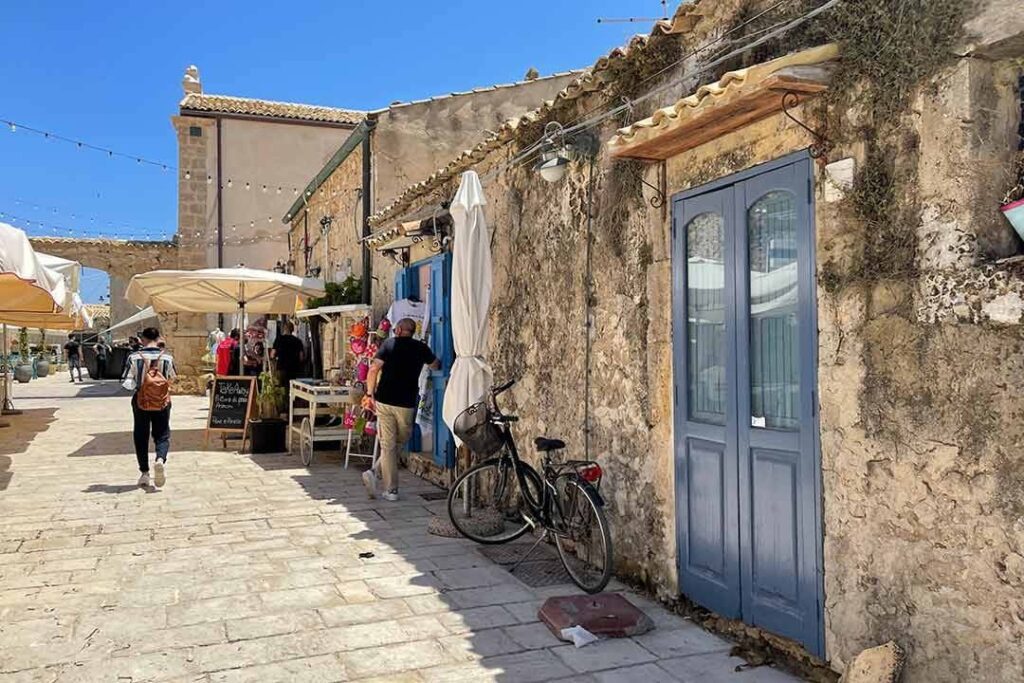 Strada con case storiche e negozi lungo un vicolo soleggiato in un paesino italiano