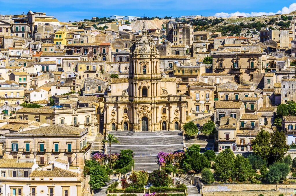 Panoramica di un antico quartiere mediterraneo con edifici storici e chiesa centrale in un contesto collinare