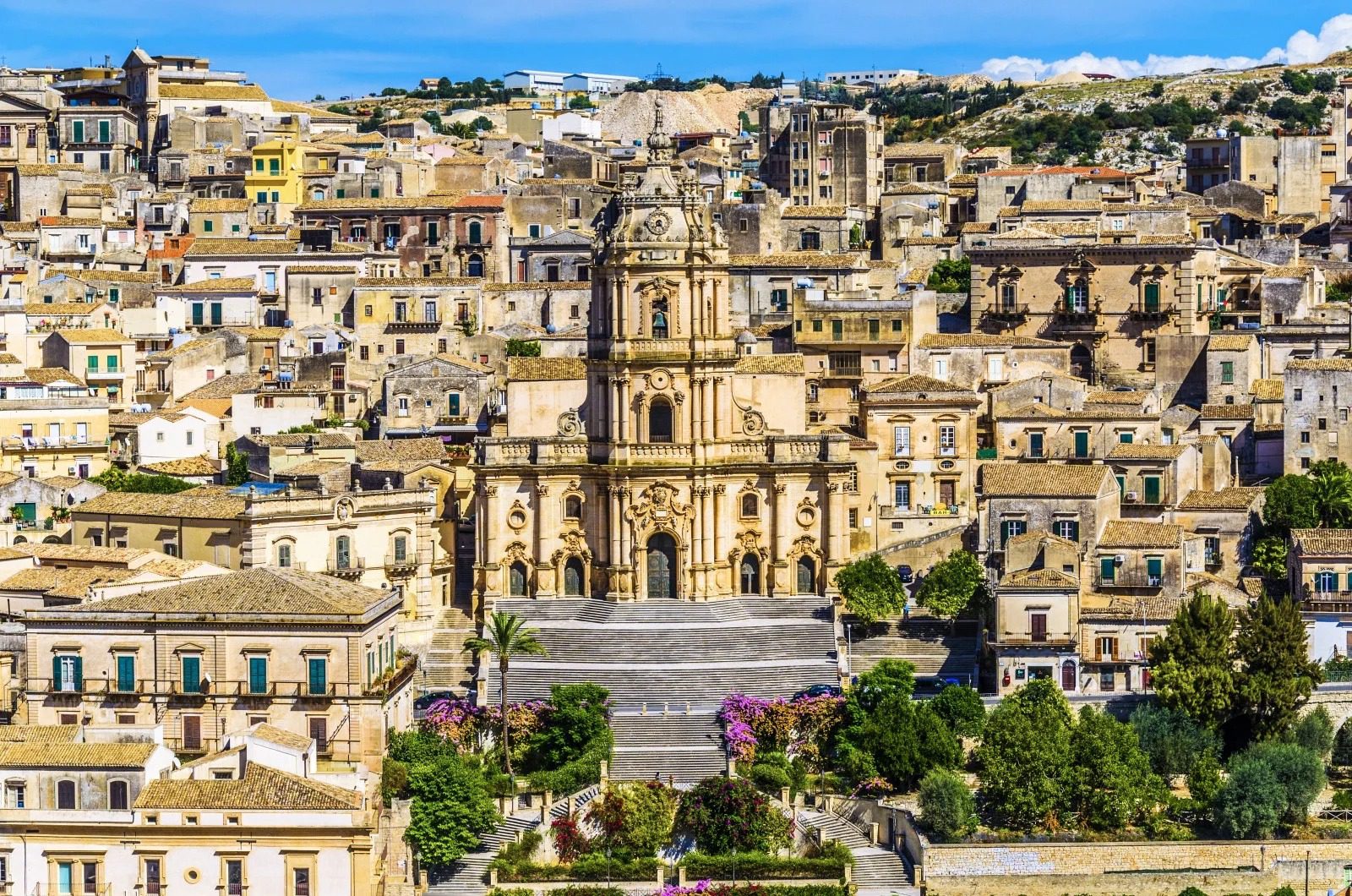 Panoramica di un antico quartiere mediterraneo con edifici storici e chiesa centrale in un contesto collinare