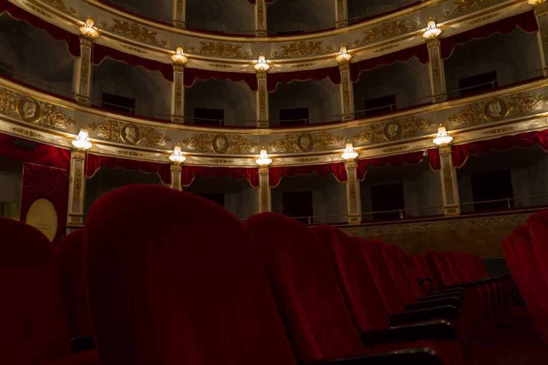 interno di un teatro con sedia rossa e palco elegante con decorazioni dorate