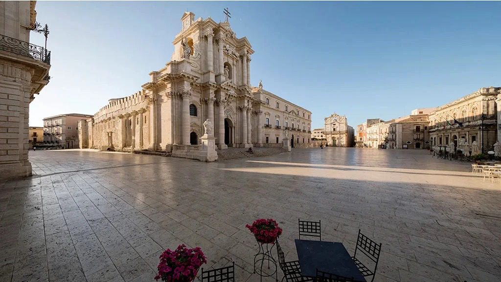 Plaza storica con imponenti edifici barocchi e spazio aperto, su una piazza affacciata su un cielo sereno