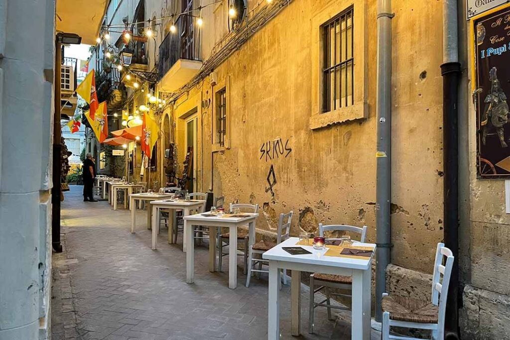 Strada pittoresca con tavoli all'aperto di ristorante e muri colorati diurni in Italia