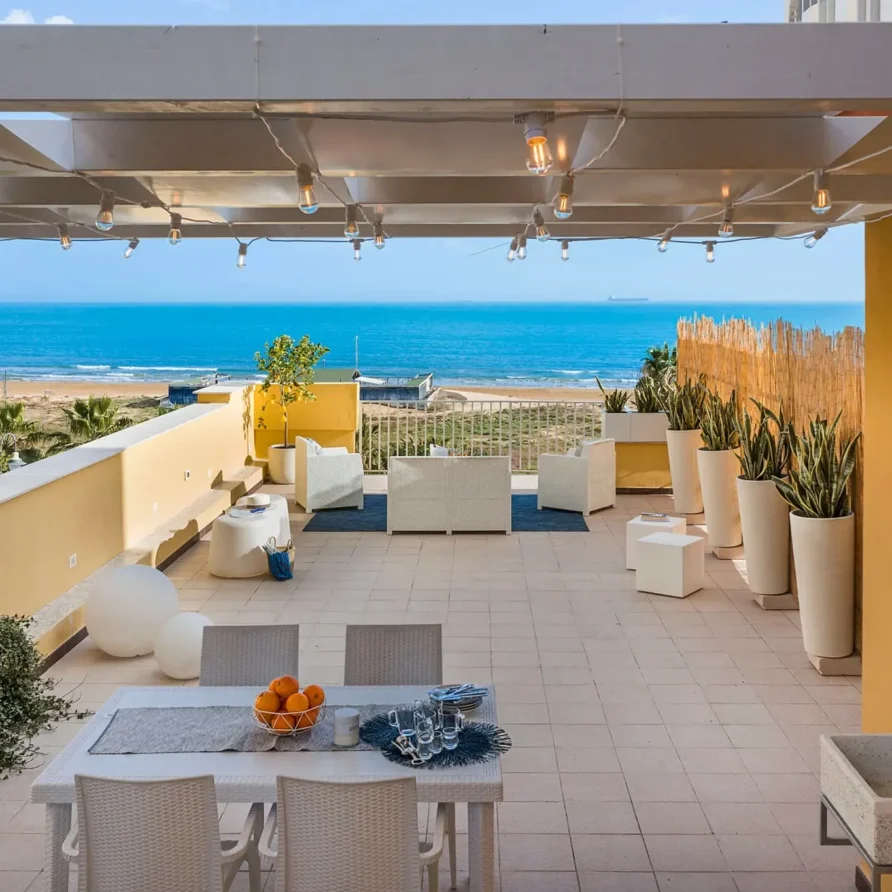 Terrazza panoramica con vista mare, arredamento elegante e piante in vaso, ideale per relax e convivialità all'aperto