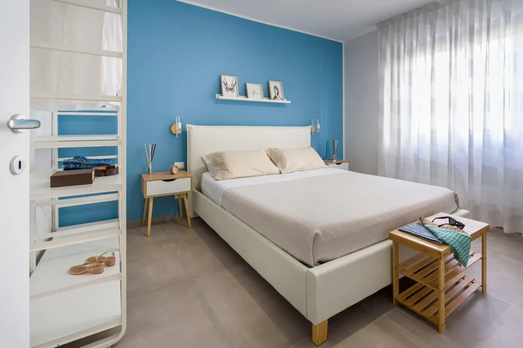 imgi_47_q Camera da letto luminosa con pareti azzurre, letto bianco, tende leggere e arredamento minimalista