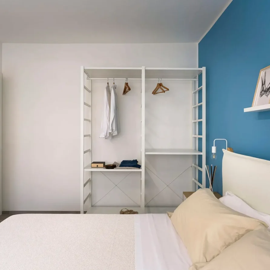 Camera da letto moderna con armadio aperto e pareti bianche e blu