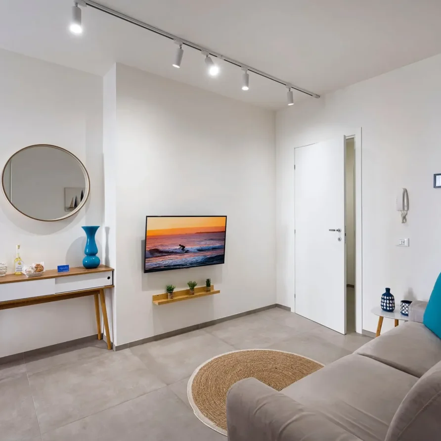 Interno di un soggiorno moderno con divano, tavolo portaoggetti, televisore e decorazioni minimaliste