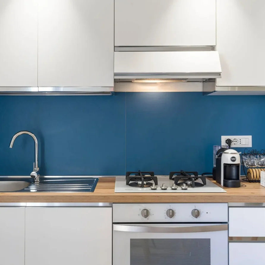 Cucina moderna con lavello, piano cottura a gas e elettrodomestici su una spaziosa superficie bianca