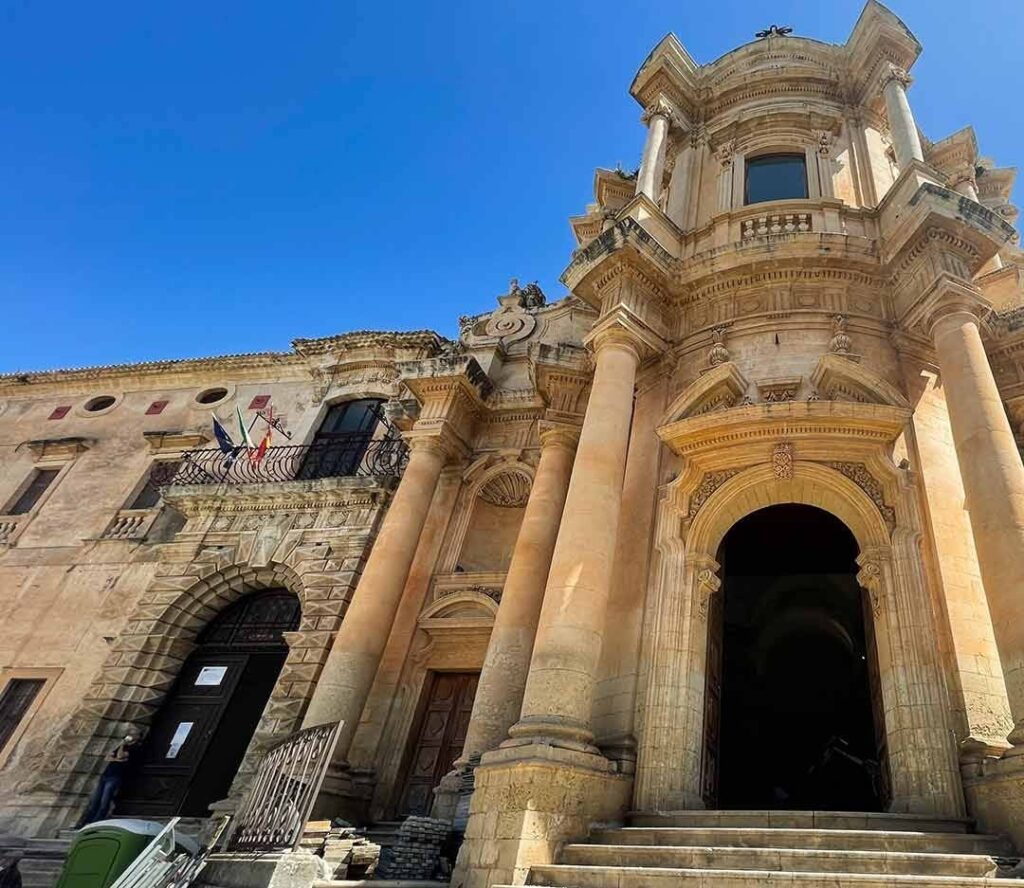 Vista frontale di un'imponente chiesa barocca con colonne e dettagli architettonici elaborati sotto un cielo azzurro