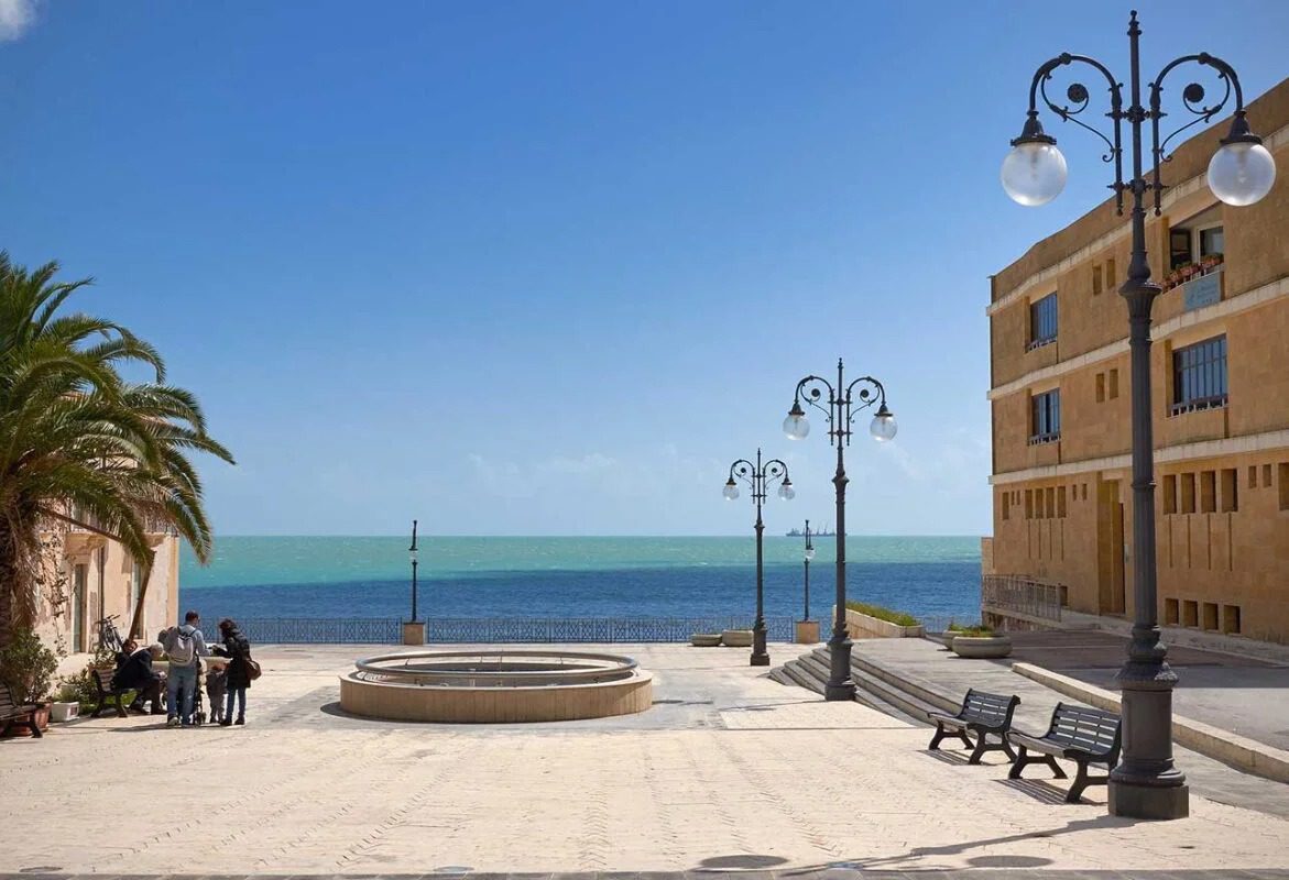Passeggiata sul lungomare con panchine, lampioni e vista sul mare e il cielo azzurro